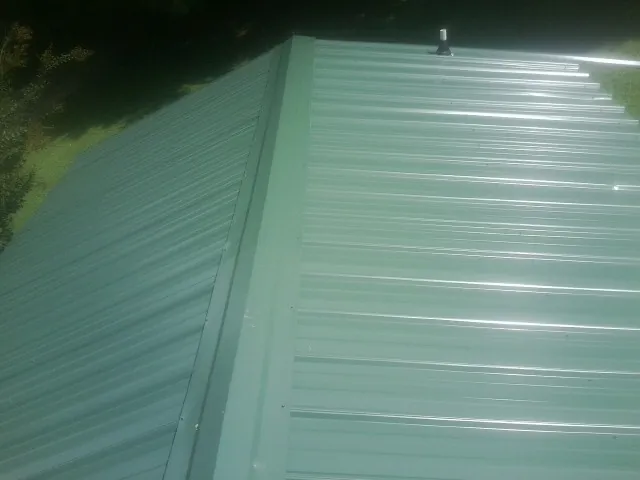 New green metal panels meeting at the ridge of a roof — Flat Roof Repair work by our crew in Madrid