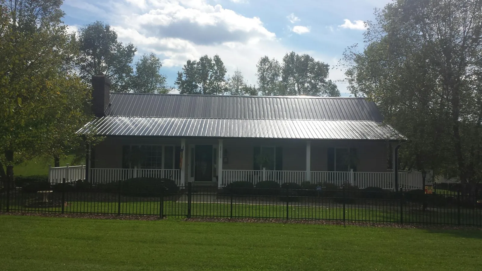 Gray metal roof on a brick ranch with a full width front porch — Gutter Guard Installation work by our crew in Madrid