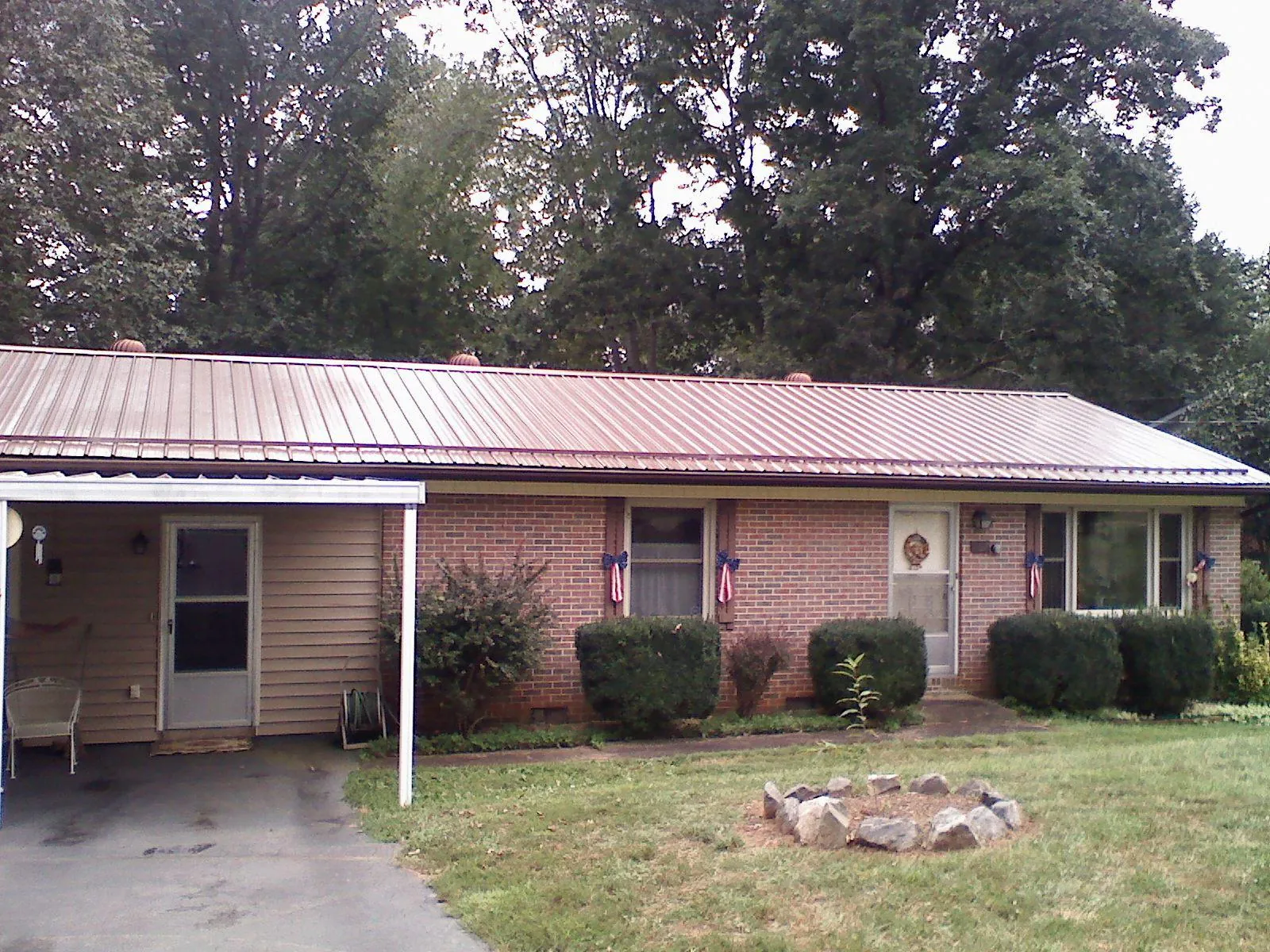 Bronze metal roof and carport on a brick ranch home — Roof Repair work by our crew in Madrid